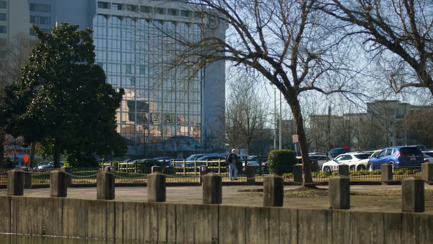 A man walks into a parking lot outside an office building