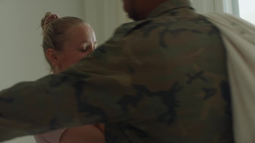 A woman holding a baby is surprised by the arrival of a man in a military camouflage uniform