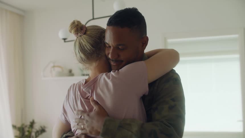 A man and woman embrace while standing indoors