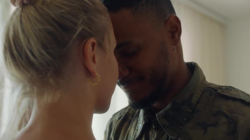 A mother and father kissing intimately while holding their baby
