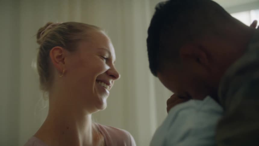 A woman laughs as a man has fun with his baby