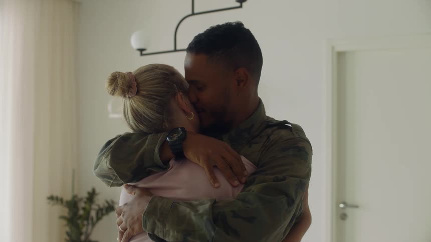 A man and a woman hugging in a room with a wall and door in the background