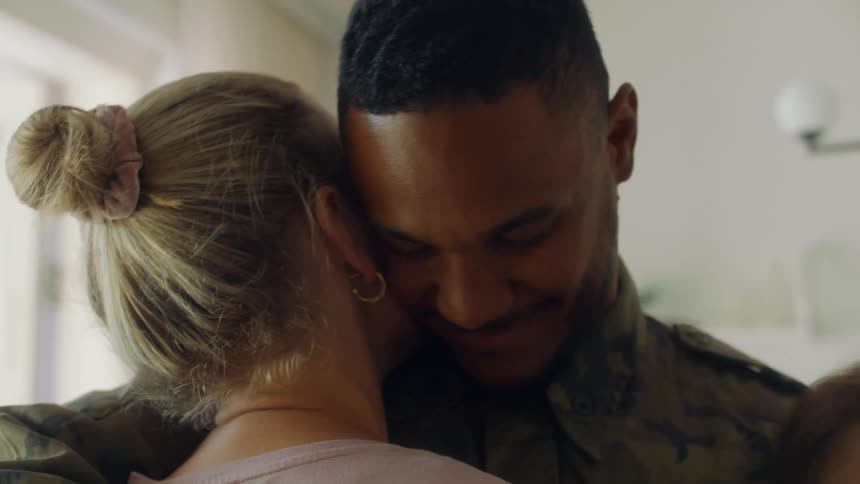 A soldier smiles as he pulls his girlfriend in for a hug