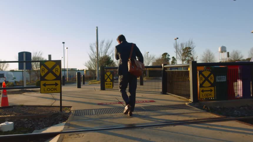 A businessman in a suit commuting to work while walking past a train terminal