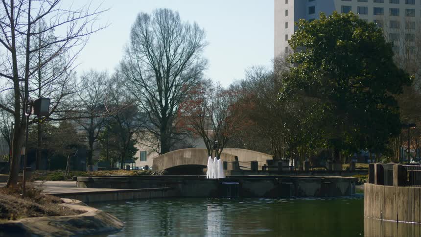 Water fountain in a park and someone walks through the park