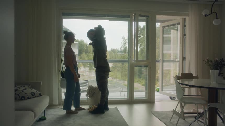 A couple is standing facing each other while the man plays with the baby