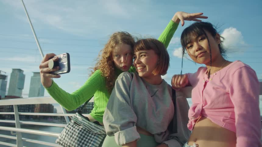 Three women pose for a selfie by the water