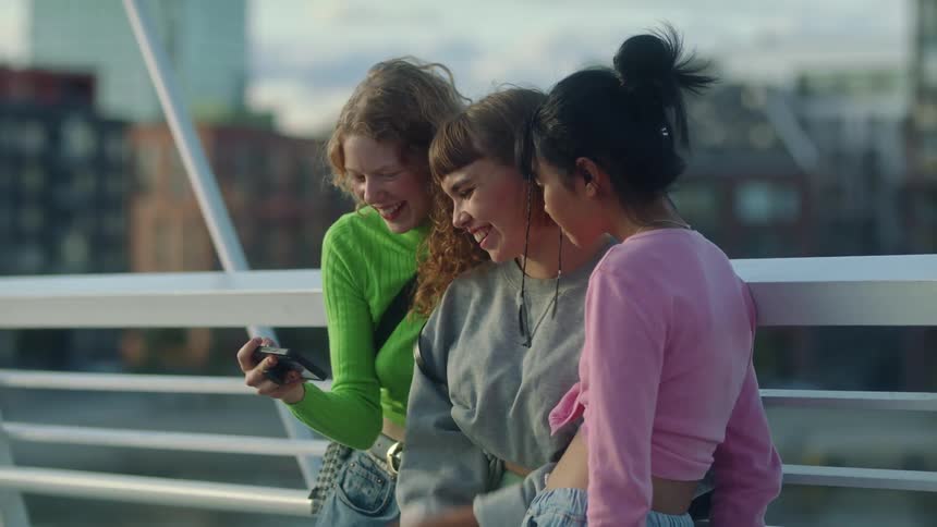 Women are standing on a bridge taking selfie pictures