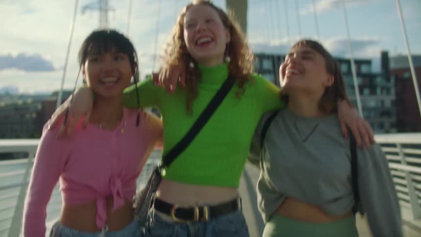 Women are walking across a footbridge in a city