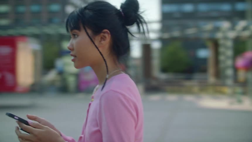 A girl walks over to her friend after photographing her with a phone