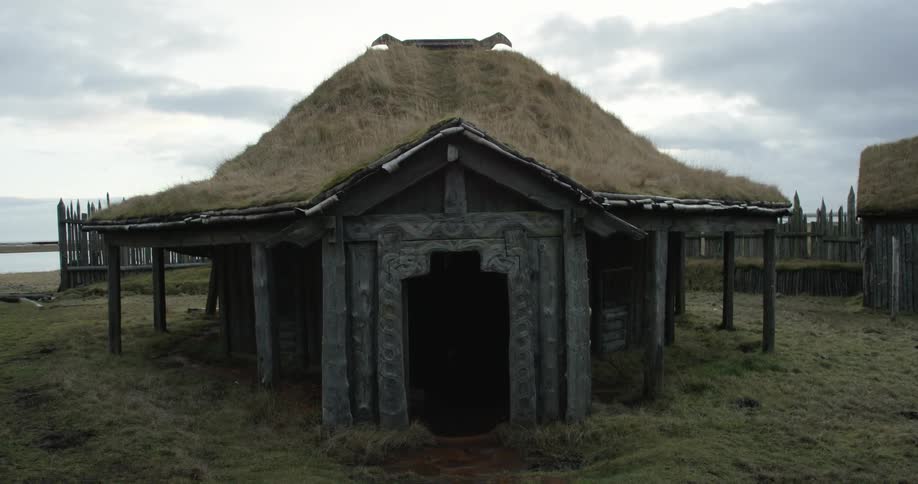 A building with a thatched roof has an ornate door opening