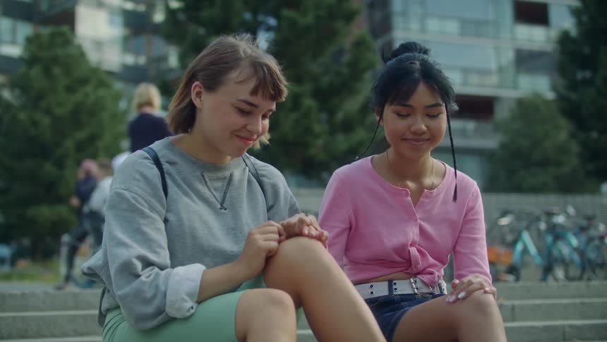 Two women sit on the steps holding hands