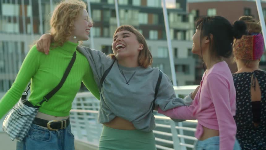 A girl is running toward two other girls and they have a group hug