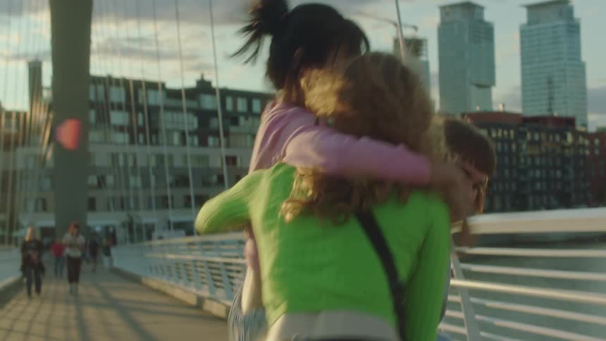Three women jump around and play as they cross the bridge