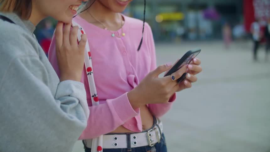 A view of two women standing outside looking at a phone