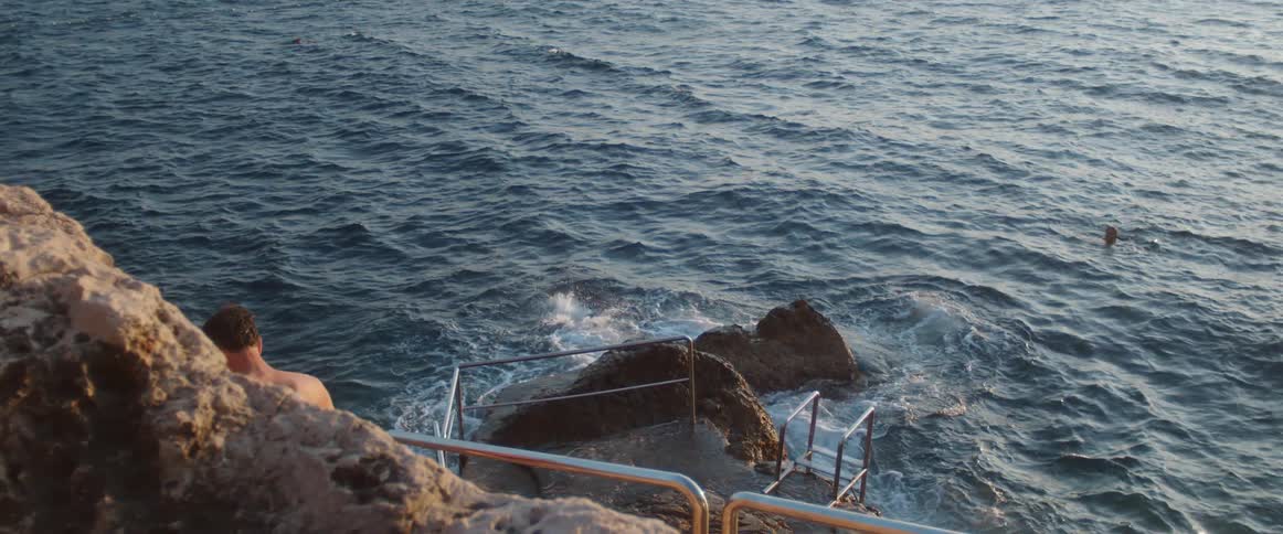 A man dives off a rock into an ocean