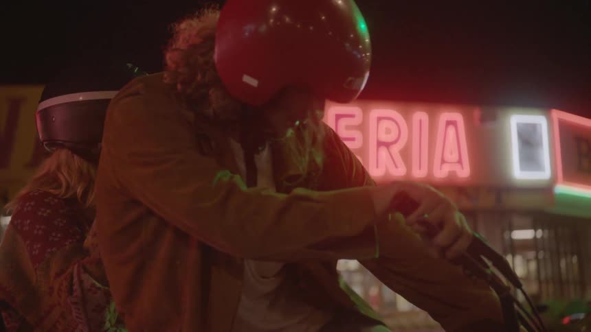 A man and women talk then put on helmets and get on a motorcycle