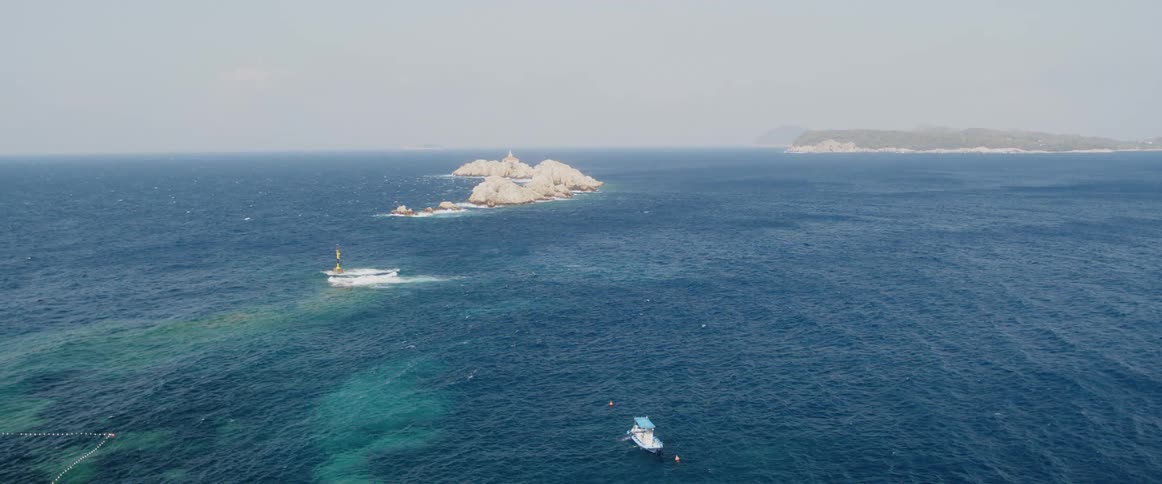 An aerial view of a boat floating off a coast in the daytime