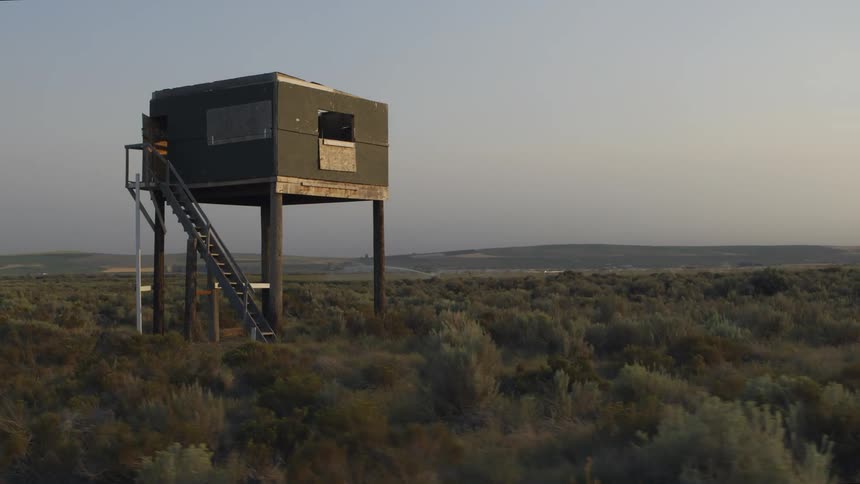 Low orbit around a hunters deer stand built along sagebrush of the open range