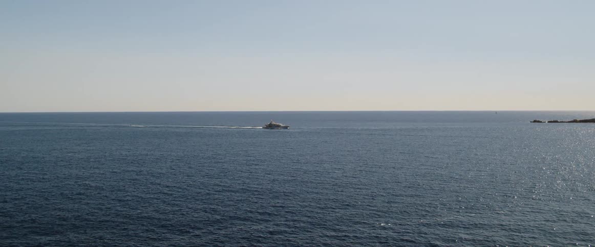 A view of the ocean with some rocks in the distance