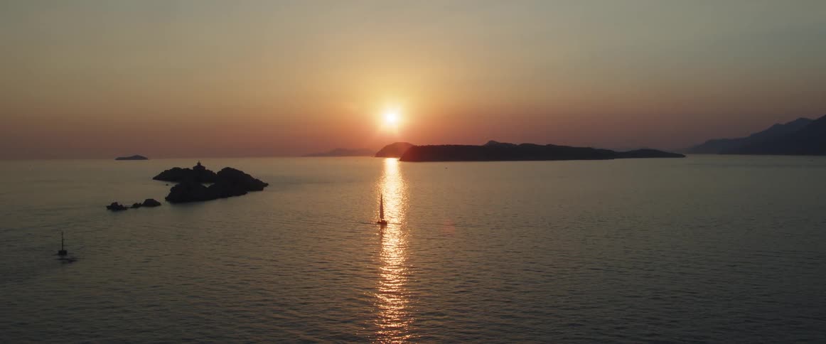 A sailboat rests in a stream of sunlight in the ocean