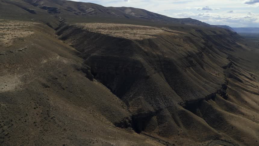 Tilt up reveal along the gnarled face of an ancient mountain slope eroded by the elements