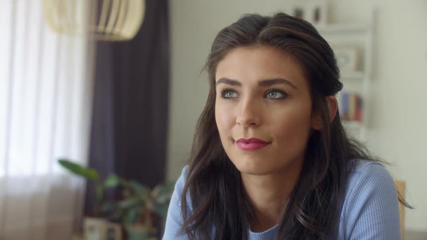 A woman is sitting in a room and smiling
