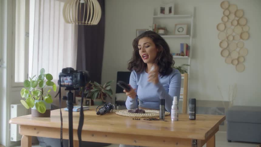 A woman records video of herself styling her hair
