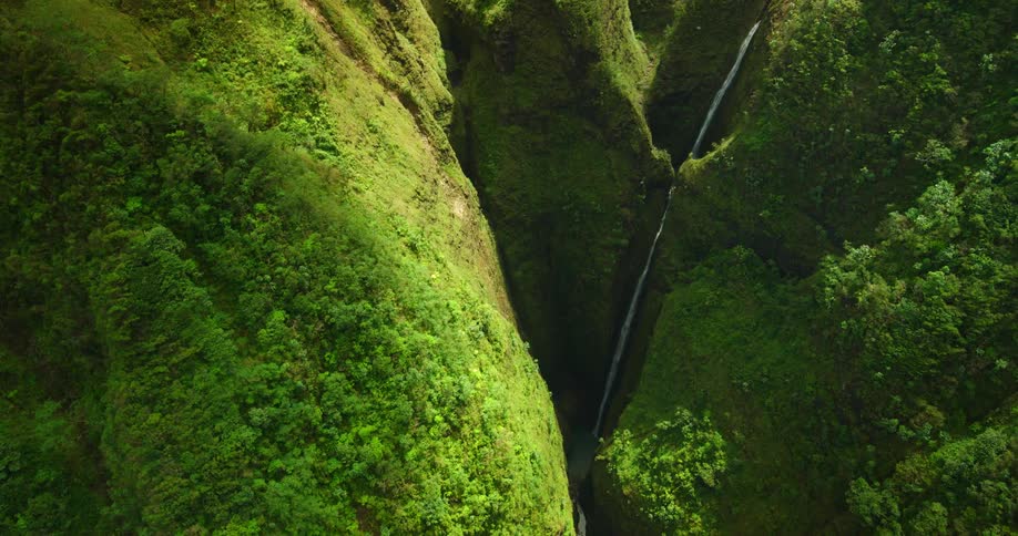 water fall running through a green mountain valley gorge