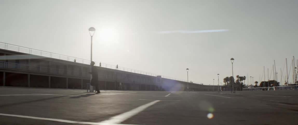 A young man jogs across a parking lot on a sunny day