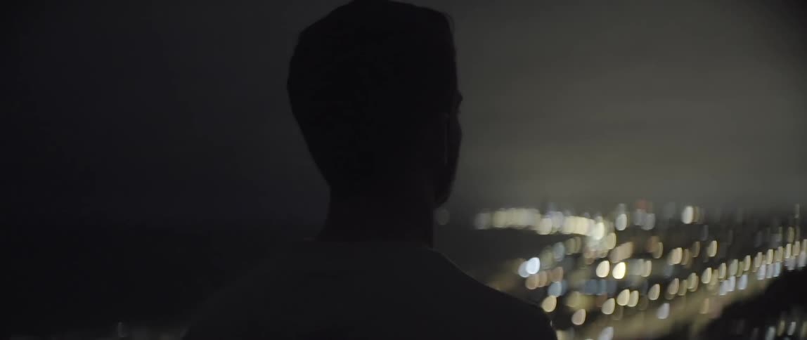 A man looks out at a city at night