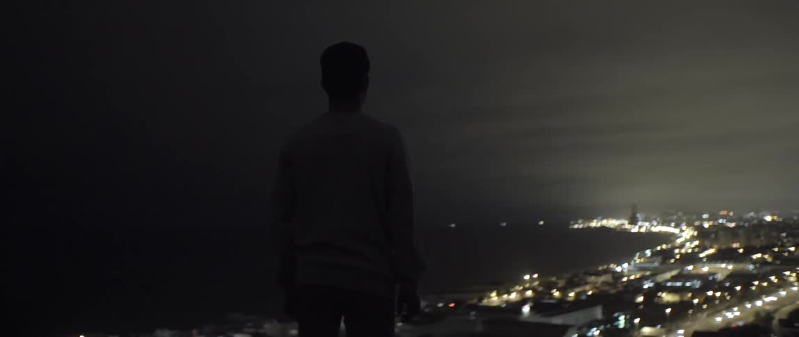 A man stands over a brightly lit area at night