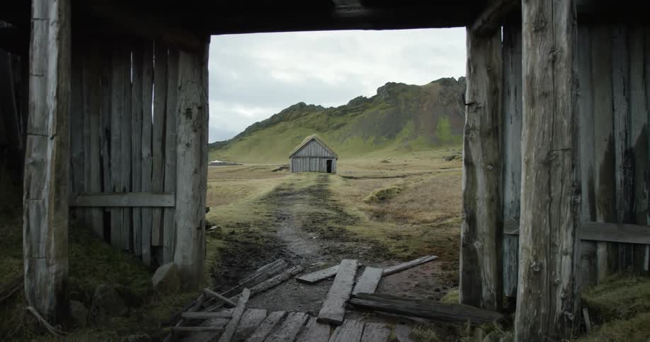 A wooden doorway leads to a barn in the distance