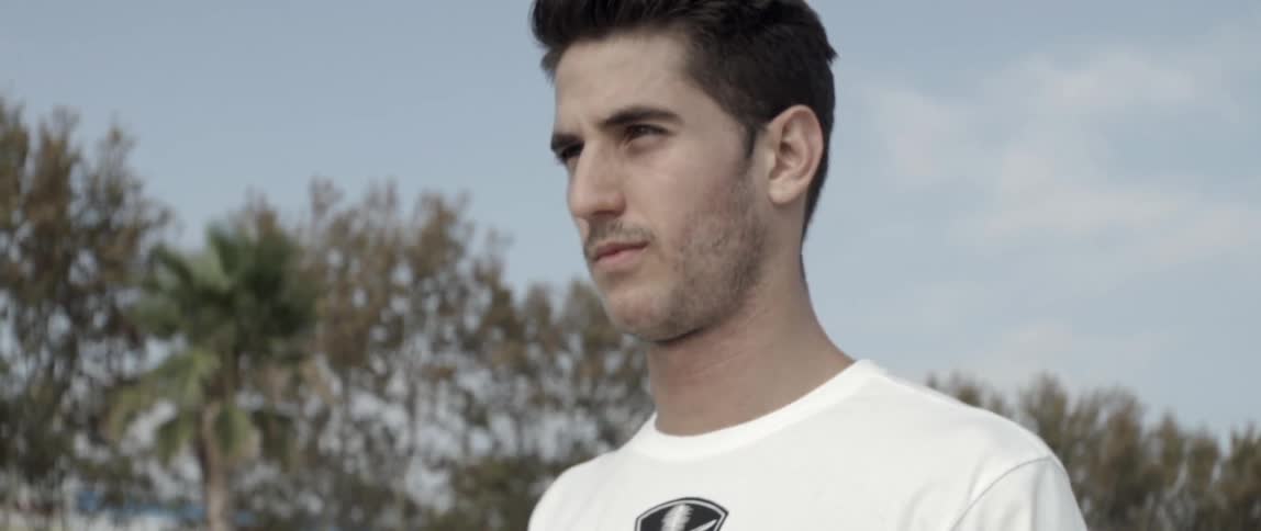 A man in a white shirt walks on a sunny day