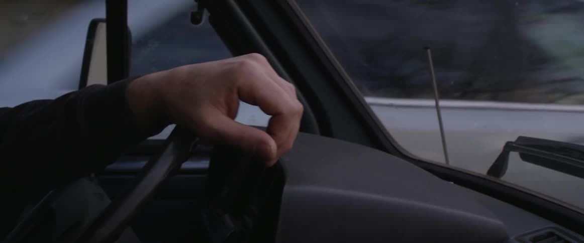 A hand is steering a wheel in a car