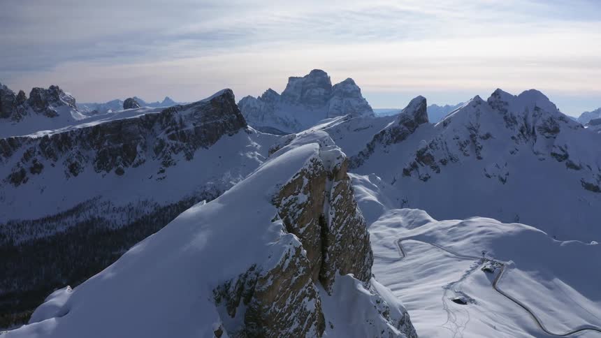 Aerial view of high snowy peak overlooking valley with forest