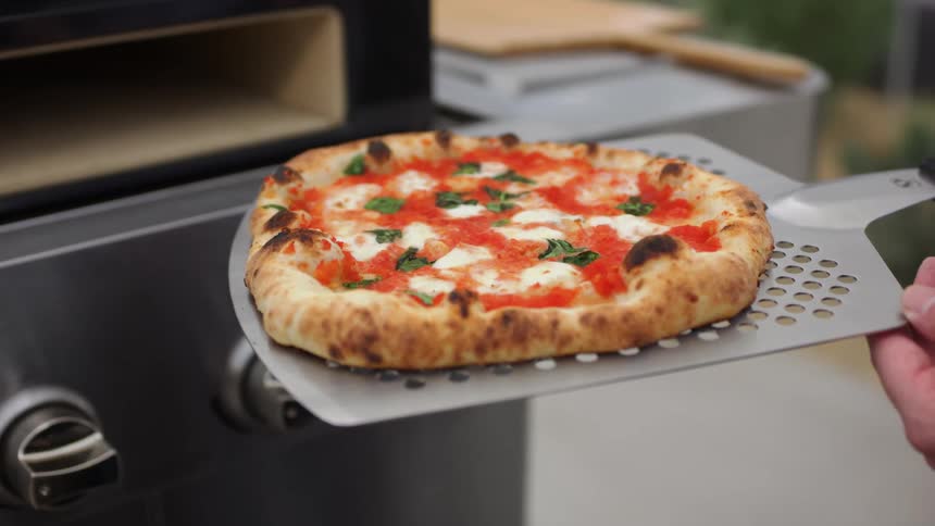 A person holding a pizza that is about to be cooked