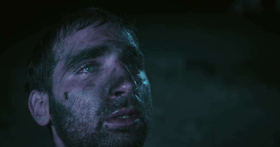 Sad young bearded man looking up with rain drops falling on his face