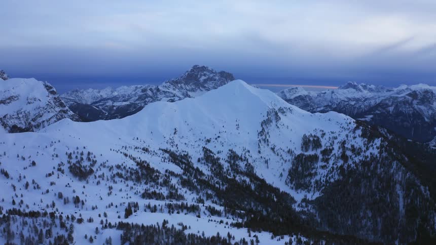 A snow covered mountain range with the sky and clouds in the background