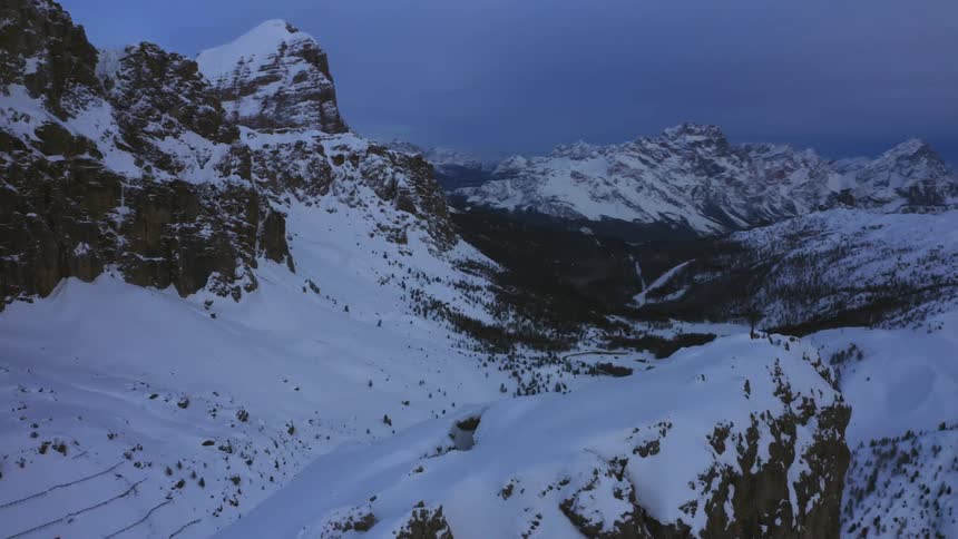 A cross is on top of a snow covered mountain peak surrounded by mountains