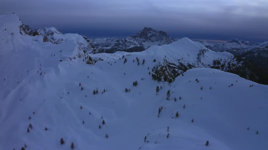 An aerial view of a snowy mountain landscape on an overcast evening