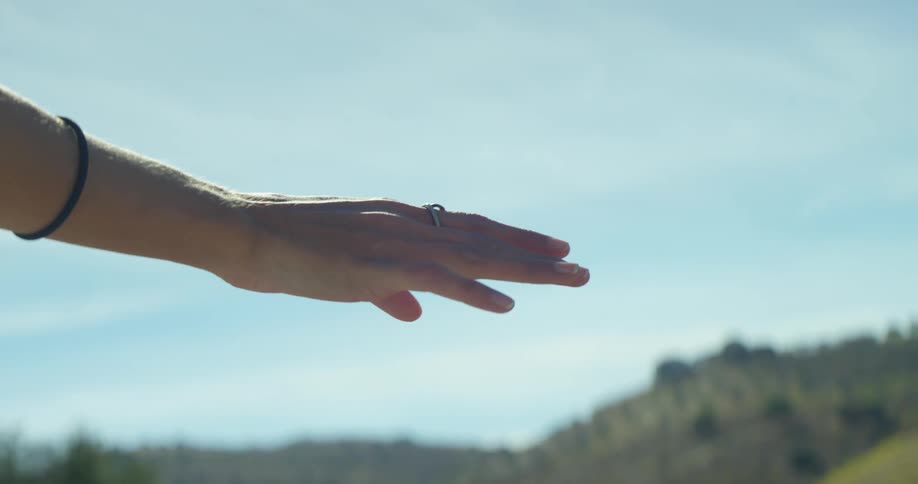 A person reaches out their hand passing by the hills