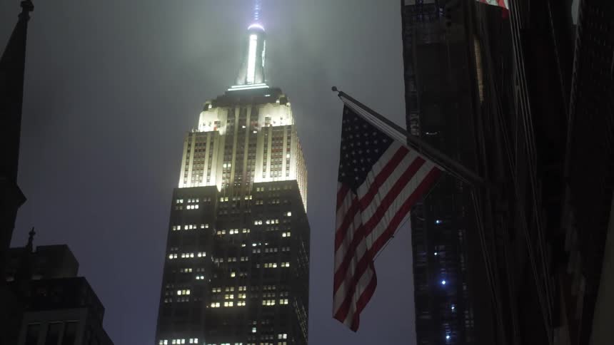 American flag in front of the emprie state building in new york city at night