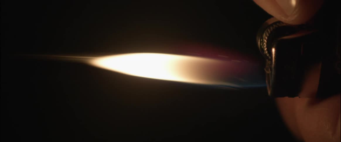 Sparks and flame shoot out of a lighter against a black background