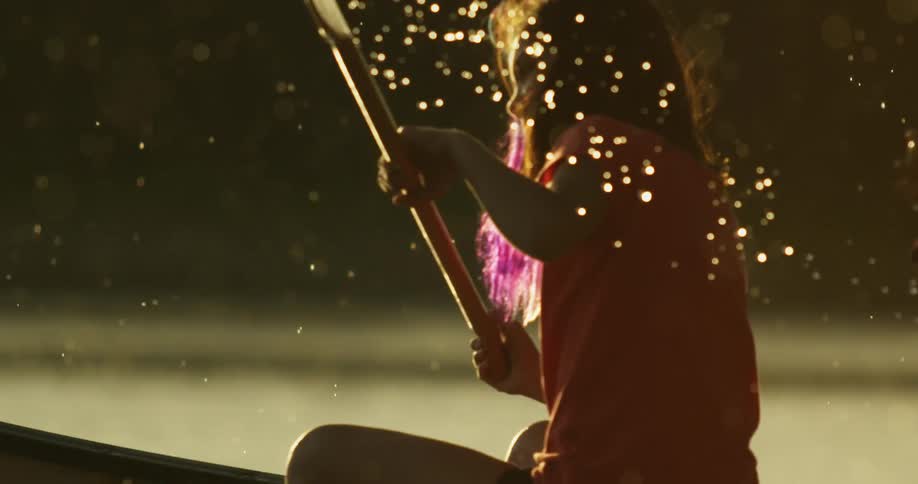 Young girl rowing a small boat on a lake under the rain