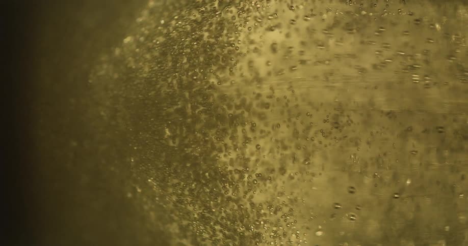 Light shines through pale amber liquid as it fizzes and bubbles