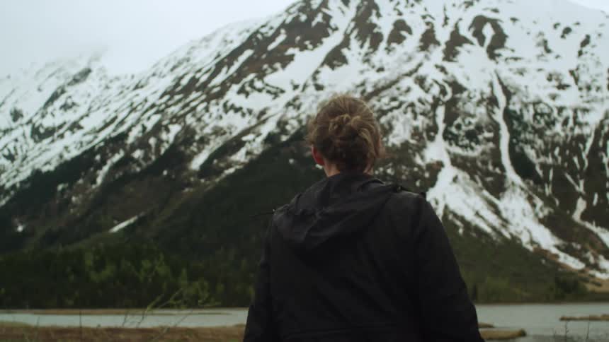 A woman walking towards a snowy mountain