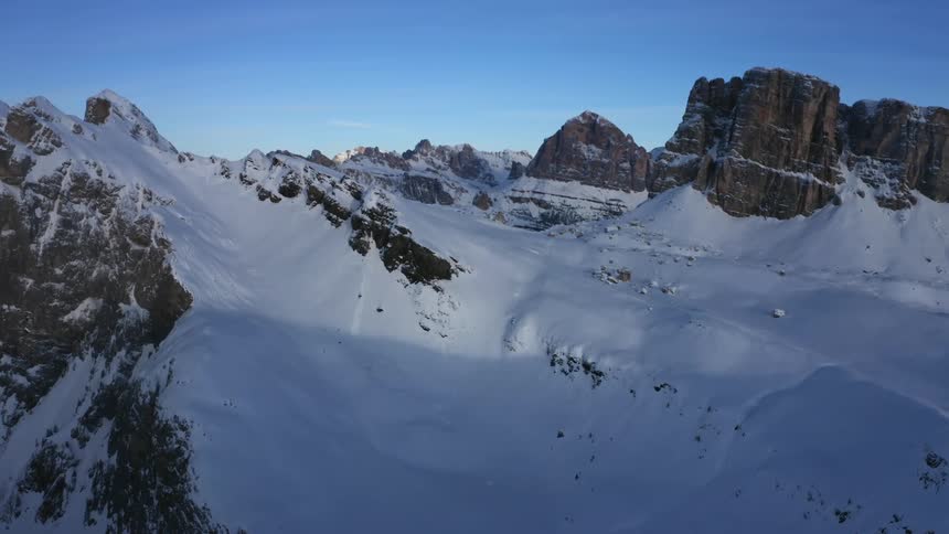 Snow covers stony mountain under azure blue sky