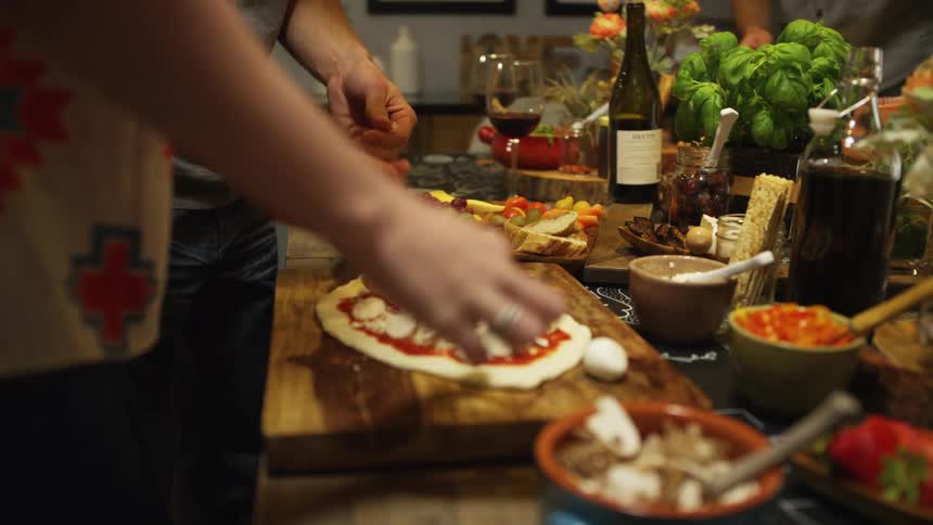Friends cooking homemade pizza with fresh ingredients