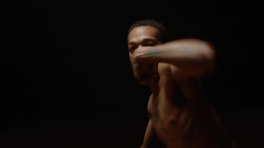 Bare chested male dancer with tattoos dance in dark area under stage light on wooden floor